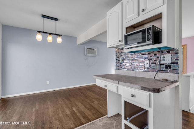 kitchen with dark wood finished floors, backsplash, an AC wall unit, white cabinetry, and baseboards