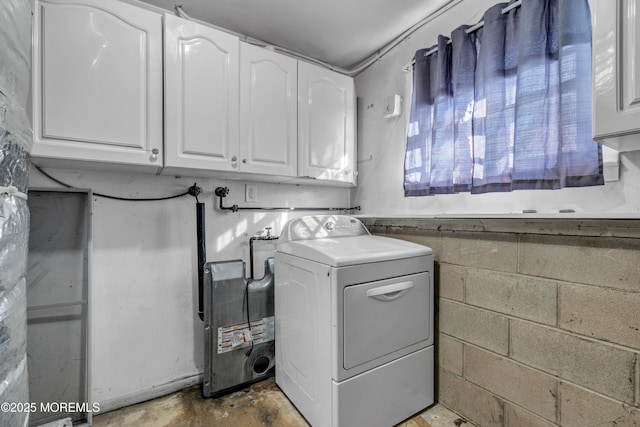 clothes washing area featuring washer / clothes dryer, cabinet space, and concrete block wall