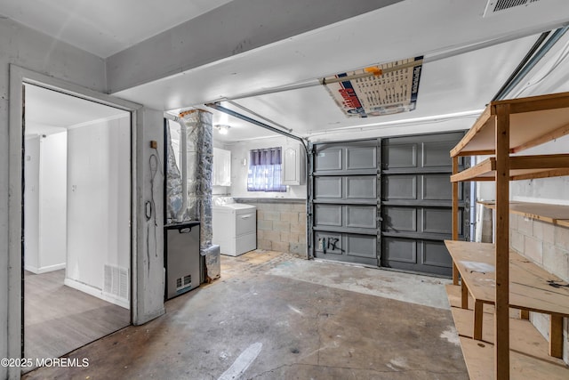 garage with concrete block wall, visible vents, and washer and dryer