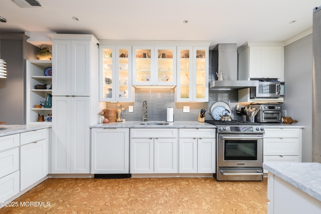 kitchen with a sink, white cabinets, appliances with stainless steel finishes, wall chimney range hood, and backsplash