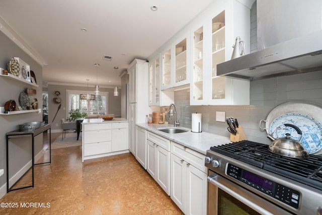 kitchen with light floors, a sink, white cabinets, stainless steel gas range oven, and wall chimney range hood