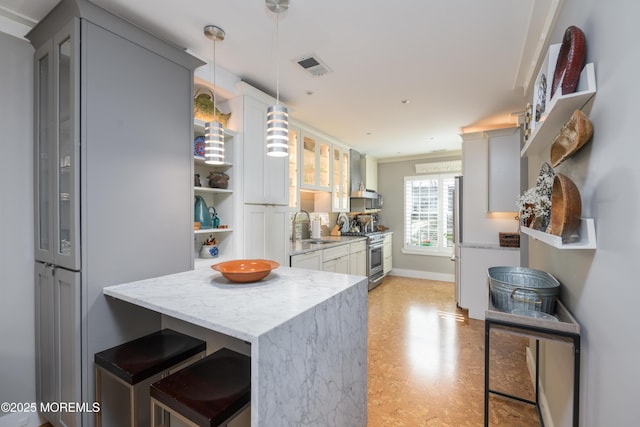 kitchen featuring visible vents, a sink, appliances with stainless steel finishes, glass insert cabinets, and light stone countertops