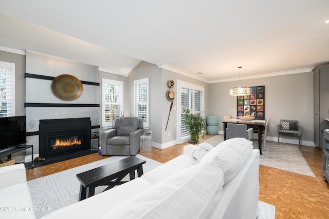 living area featuring baseboards, a large fireplace, lofted ceiling, and crown molding