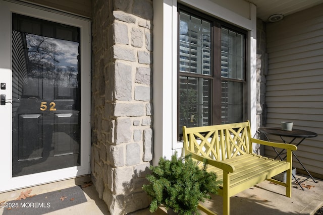 view of exterior entry with covered porch and stone siding