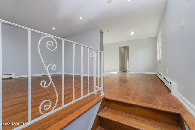 staircase with a baseboard heating unit, wood-type flooring, and baseboards