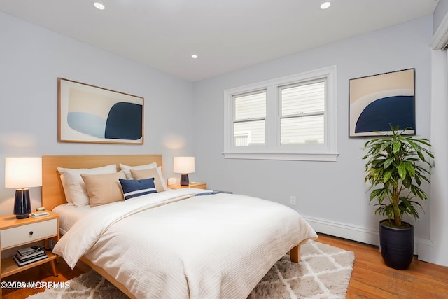 bedroom featuring recessed lighting, a baseboard radiator, and wood finished floors