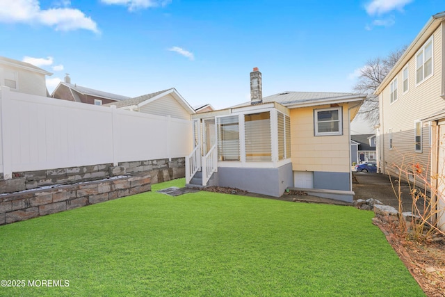 rear view of property featuring a lawn, a chimney, and fence