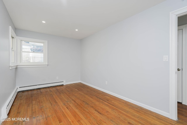 spare room featuring baseboards, baseboard heating, and hardwood / wood-style floors