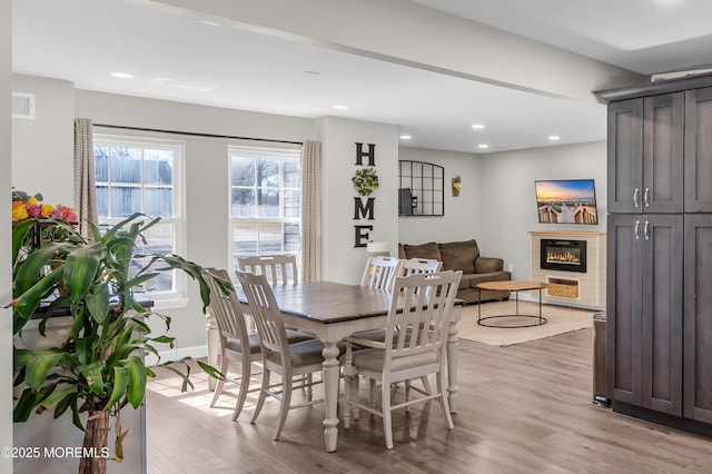 dining space featuring light wood-style floors, recessed lighting, visible vents, and a glass covered fireplace