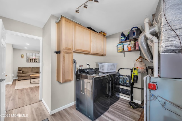 washroom featuring light wood-style flooring, washer and dryer, cabinet space, and baseboards