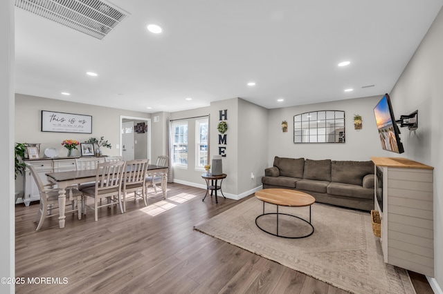 living room with baseboards, visible vents, wood finished floors, and recessed lighting