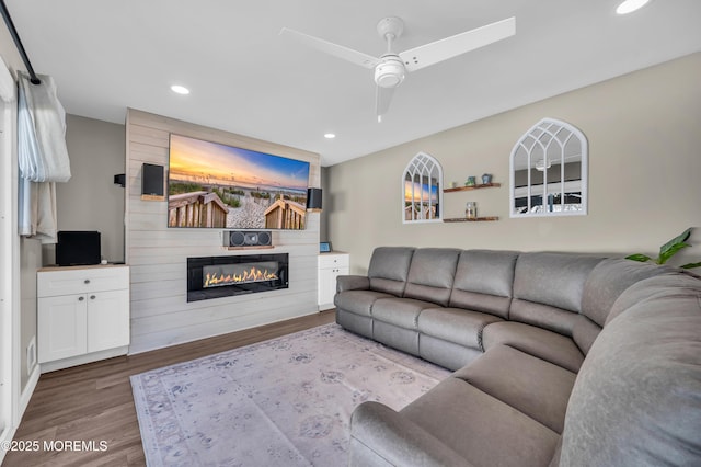 living area with recessed lighting, a large fireplace, ceiling fan, and wood finished floors