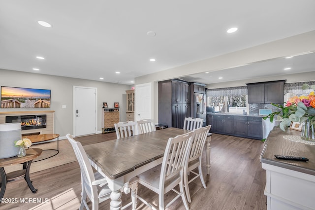 dining space featuring light wood-style floors, recessed lighting, baseboards, and a glass covered fireplace