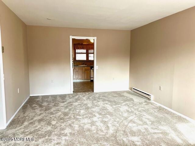 spare room with a baseboard heating unit and carpet flooring