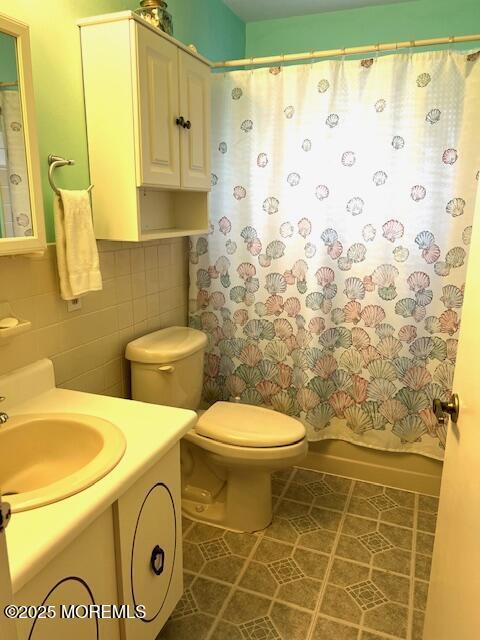 bathroom featuring toilet, vanity, tile walls, tile patterned floors, and shower / bath combination with curtain