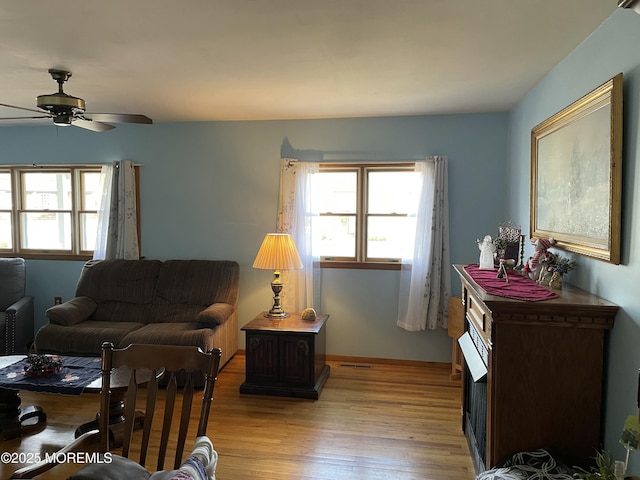 living room with light wood-style flooring, visible vents, and ceiling fan