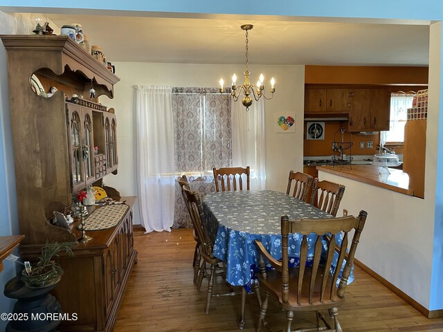 dining space featuring baseboards, an inviting chandelier, and wood finished floors