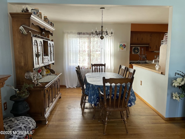 dining area with light wood-style floors, baseboards, and a chandelier