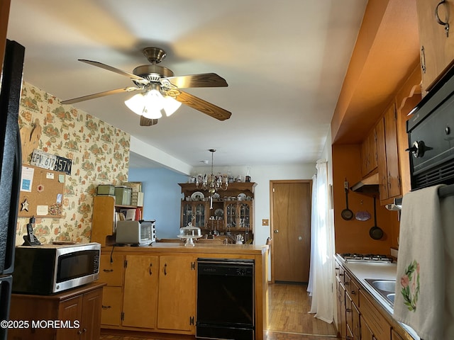 kitchen with light wood-style floors, dishwasher, stainless steel microwave, stovetop, and under cabinet range hood