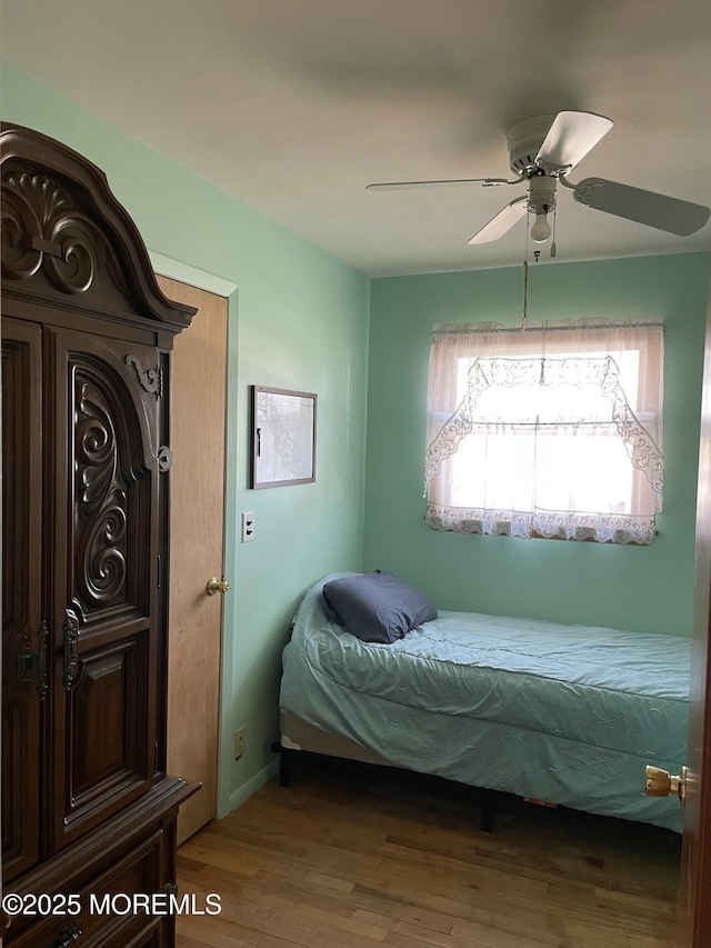 bedroom featuring wood finished floors, a ceiling fan, and baseboards