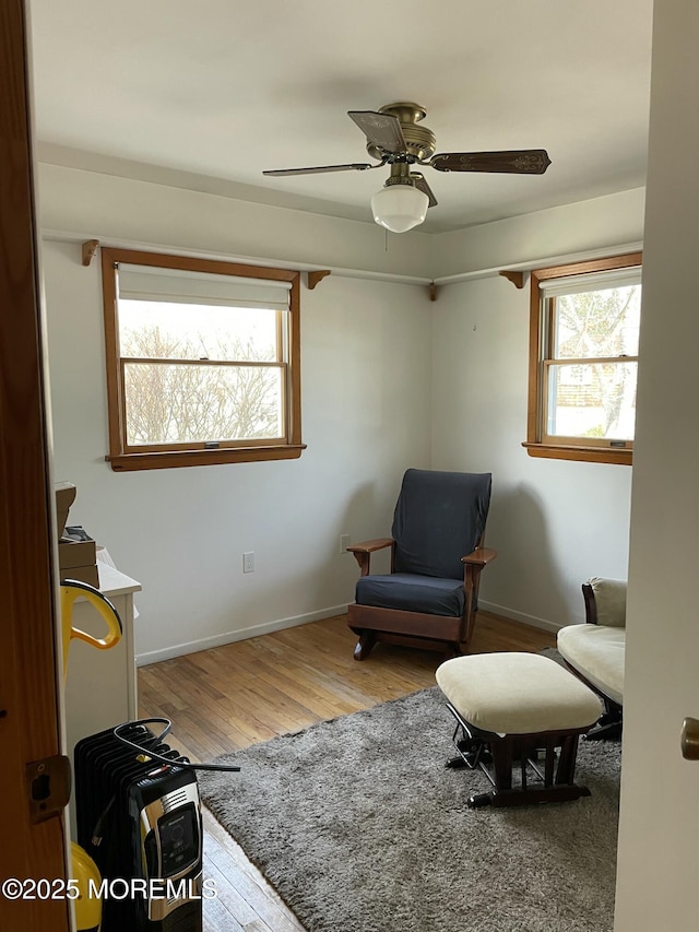 living area with ceiling fan, baseboards, and wood finished floors