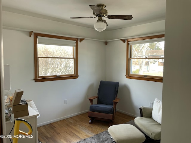 living area with ceiling fan, baseboards, and wood finished floors