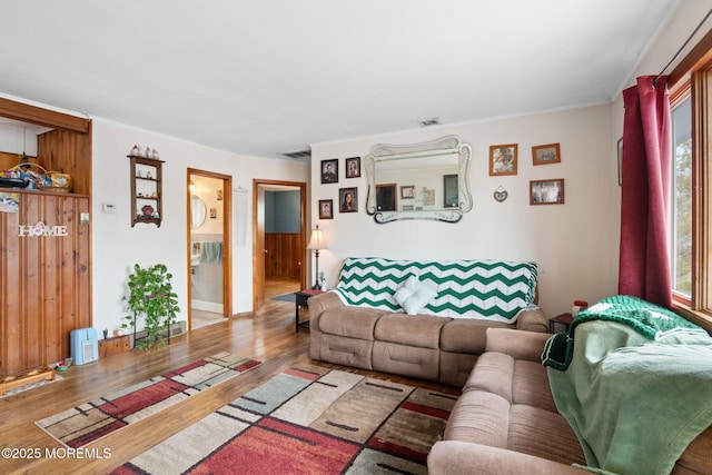 living area with crown molding, visible vents, and wood finished floors