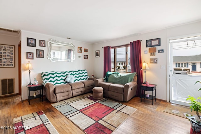 living room with ornamental molding, visible vents, and hardwood / wood-style floors