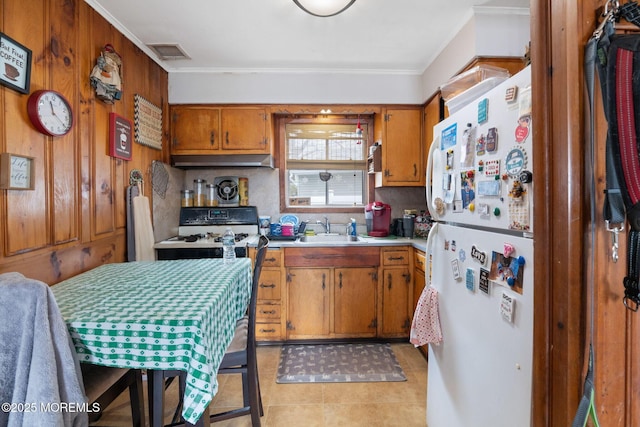 kitchen featuring brown cabinets, light countertops, visible vents, a sink, and under cabinet range hood