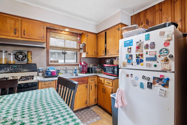 kitchen featuring freestanding refrigerator, light countertops, under cabinet range hood, black microwave, and gas stove