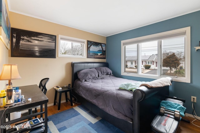 bedroom with crown molding, baseboards, and wood finished floors