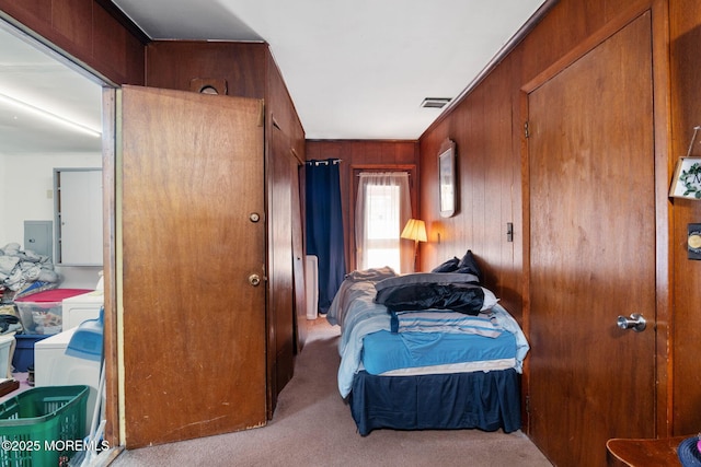 carpeted bedroom featuring wood walls and visible vents