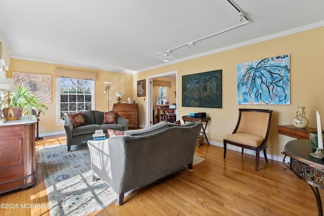 living area with ornamental molding, light wood-style flooring, and baseboards