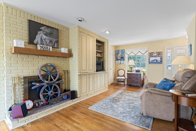 living area featuring a brick fireplace and light wood finished floors