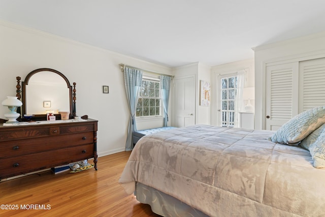 bedroom with multiple closets, multiple windows, crown molding, and light wood finished floors