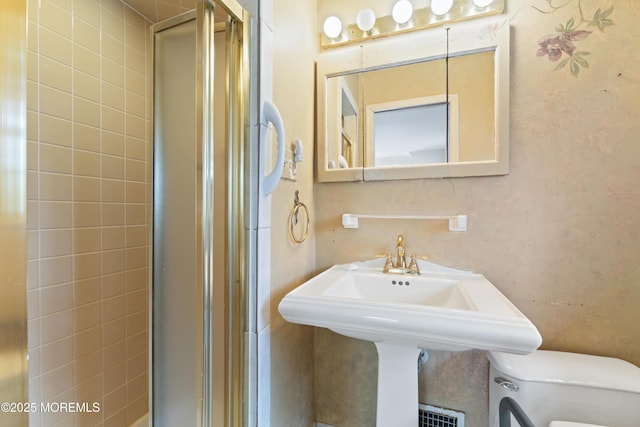 bathroom featuring toilet and a shower stall