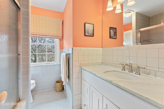 full bathroom with toilet, a shower with shower door, vanity, tile walls, and tile patterned floors