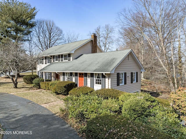 view of front of home featuring a chimney and roof with shingles