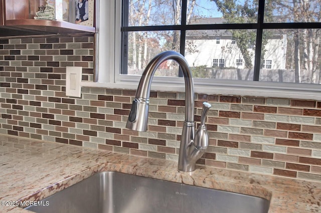 details with tasteful backsplash, a sink, and light stone counters