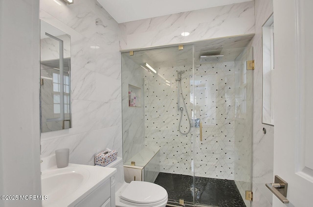 bathroom with vanity, a shower stall, toilet, and tile walls