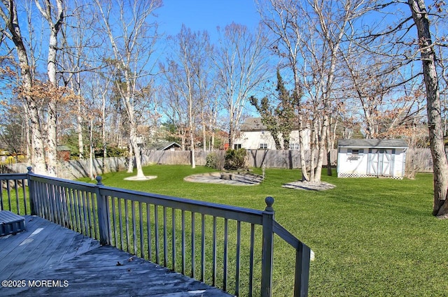 view of yard with an outbuilding, a storage shed, a fenced backyard, and a wooden deck