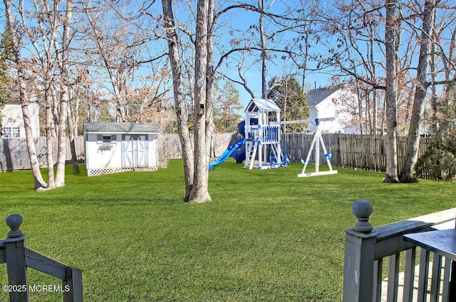 view of yard with an outbuilding, a fenced backyard, a playground, and a storage unit