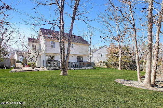 rear view of house with a deck, a lawn, and fence