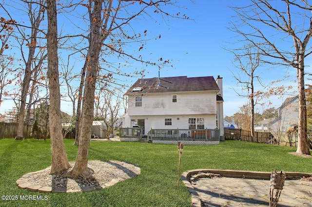 back of house with a fenced backyard, a chimney, a deck, and a lawn