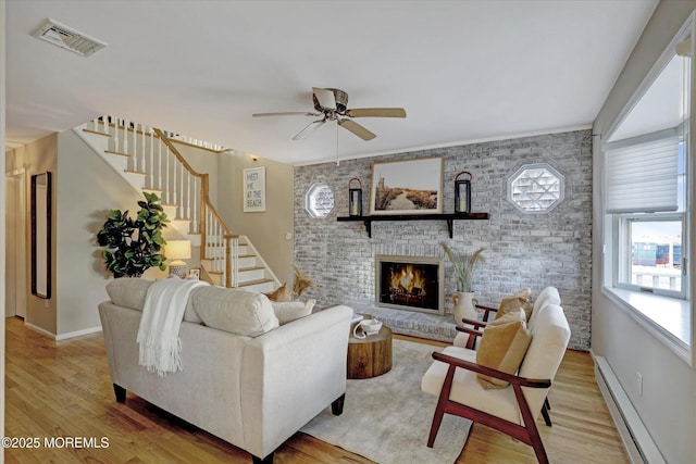 living area with light wood-type flooring, stairway, a baseboard radiator, and visible vents