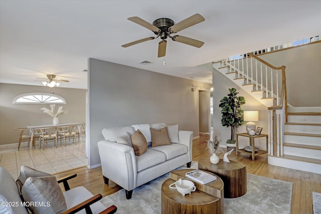 living area featuring visible vents, ceiling fan, wood finished floors, baseboards, and stairs