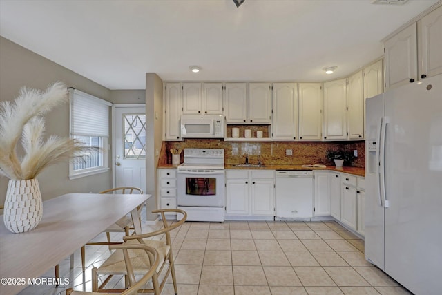 kitchen featuring white appliances, light tile patterned flooring, a sink, and decorative backsplash