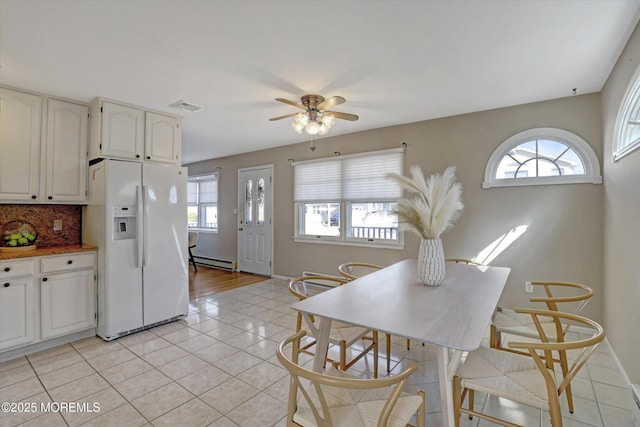 kitchen with light tile patterned floors, a baseboard radiator, white refrigerator with ice dispenser, and decorative backsplash