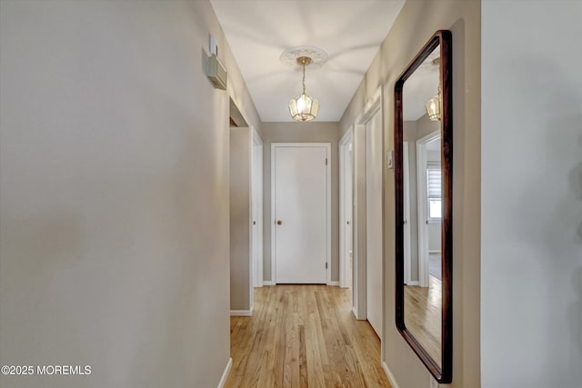 corridor featuring light wood finished floors and baseboards