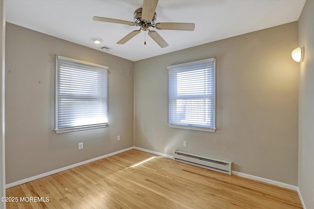 empty room featuring ceiling fan, a baseboard heating unit, visible vents, baseboards, and light wood finished floors